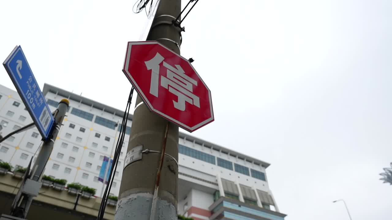 Low angle pan of a Chinese red stop traffic sign with a kanji script on a Shanghai street showing local signage