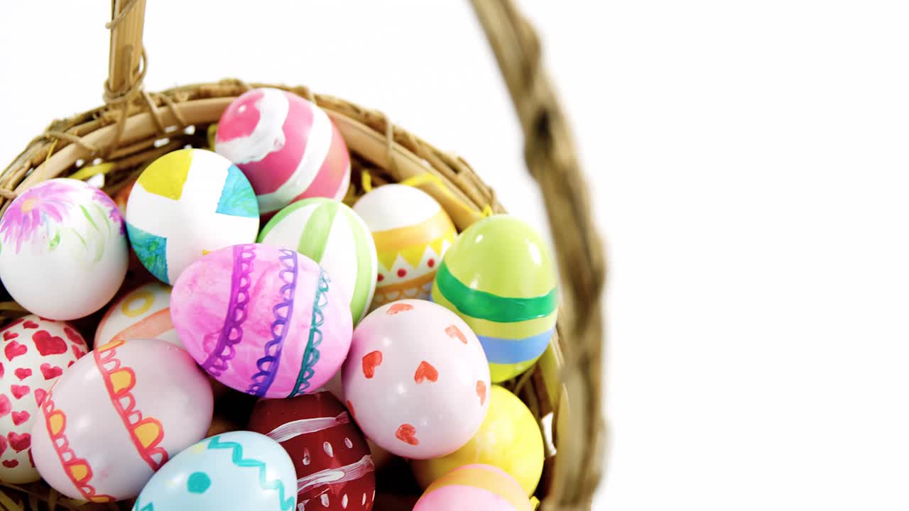Cesto con uova di Pasqua dipinte su sfondo bianco