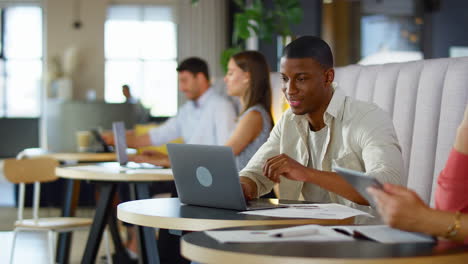 businessman working on laptop in informal seating area of modern office