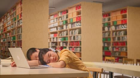 앉아서 잠을 자고 도서관에서 노트북과 함께 테이블에 책을 읽는 아시아 여성 학생