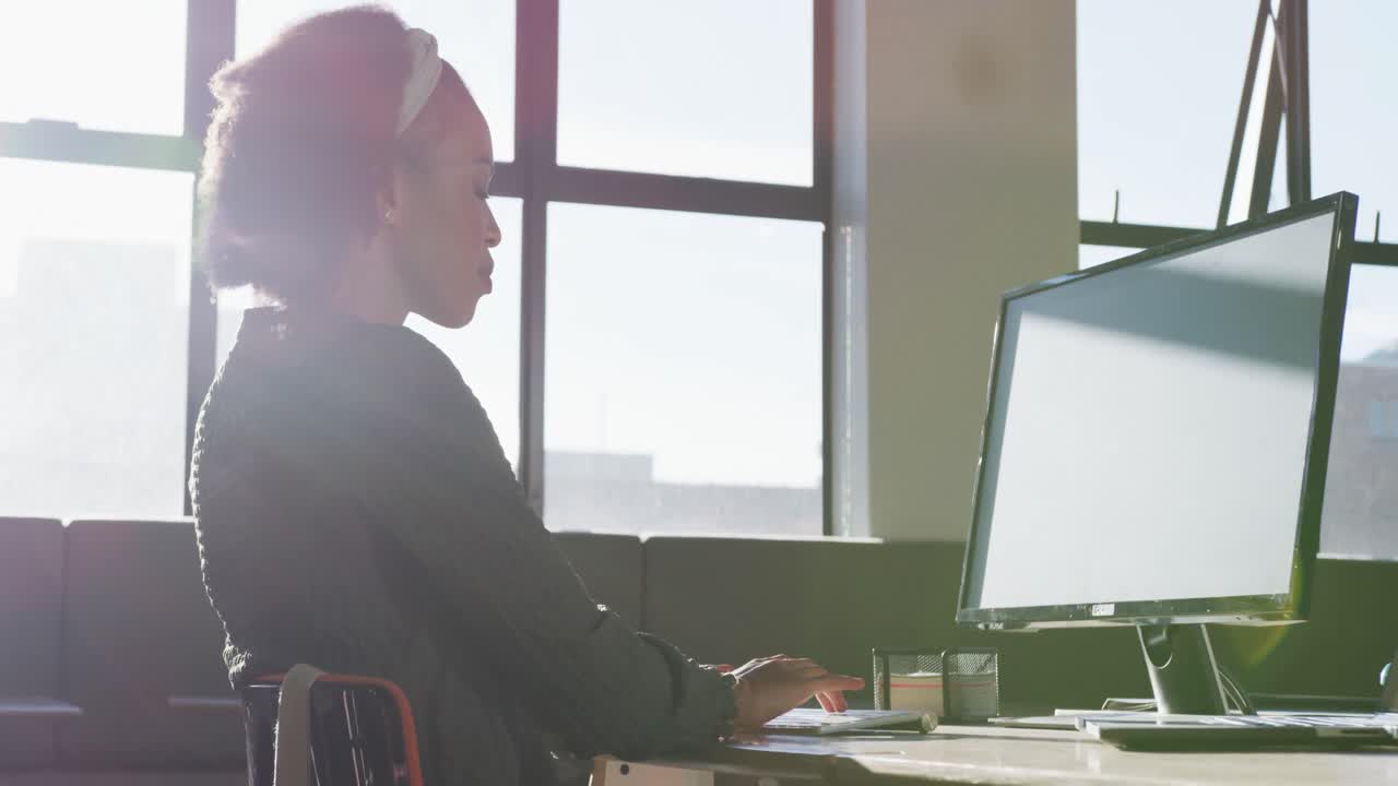 African american businesswoman sitting at table and using computer at office