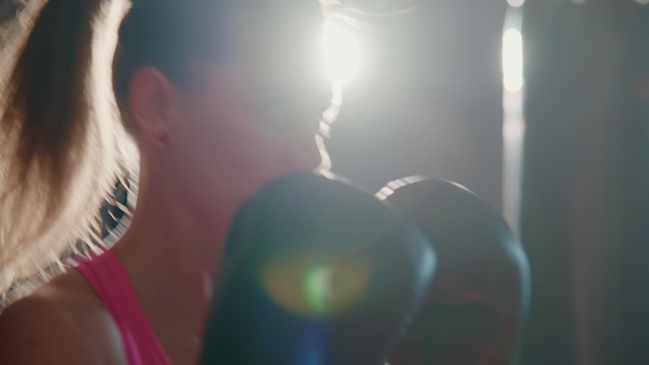 Primo piano di donna determinata che fa boxe con i guantoni in palestra