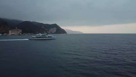 moody sky as santa catalina express ship departs from avalon bay, california, drone tracking shot