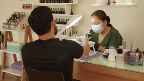 latin mexican manicurist while man guy male manicure session treatment procedure at sap wellness center resort luxury