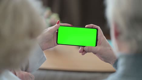 senior old couple using smartphone with green chroma key screen