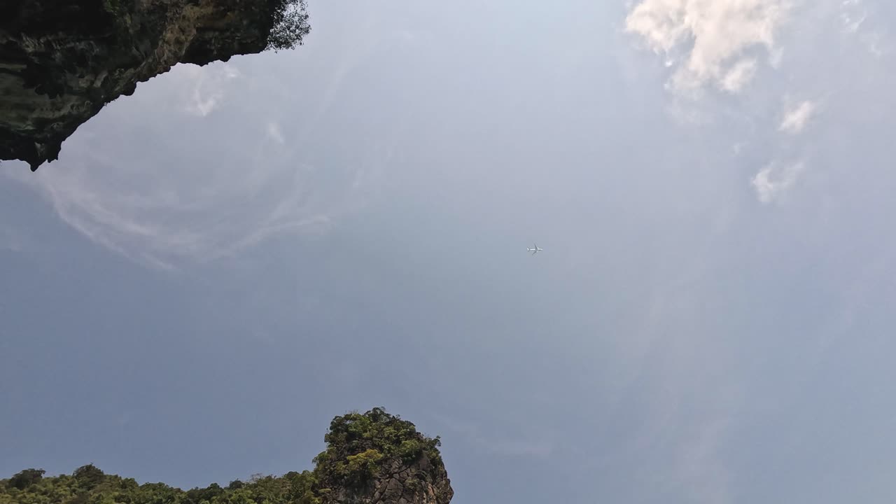 Camera tilts down revealing tropical limestone cliff.