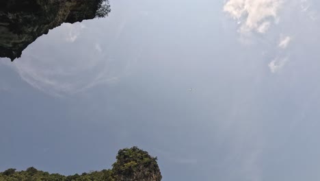 camera tilts down revealing tropical limestone cliff.