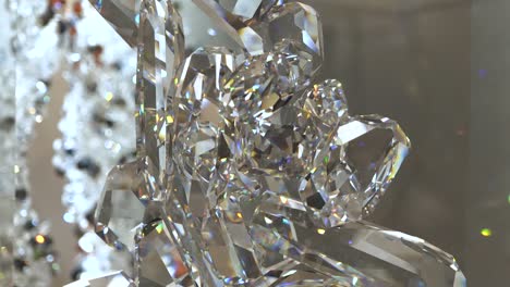 4k orbita alrededor de una escultura de cristal brillante con luces brillantes y coloridas que se reflejan en ella con más cristales en el fondo visibles mientras se mueve