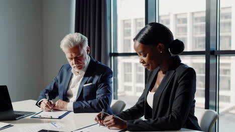 business professionals writing documents in an office meeting