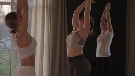 in slow motion a yoga instructor conducts a group lesson for women of different ages and weight categories thin and full in the gym in the morning in the sun. the glare of the sun on the floor