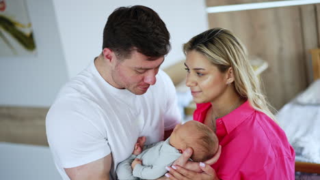 parents with their newborn baby. couple looking at baby with love and adoration. blurred backdrop.