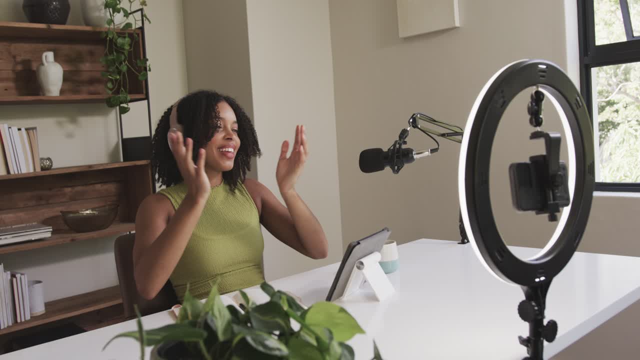 Woman starting recording grabbing headphones, adjusting, speaking into tablet mic at desk