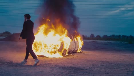 man in business suit dancing a moon walk against the background of burning car