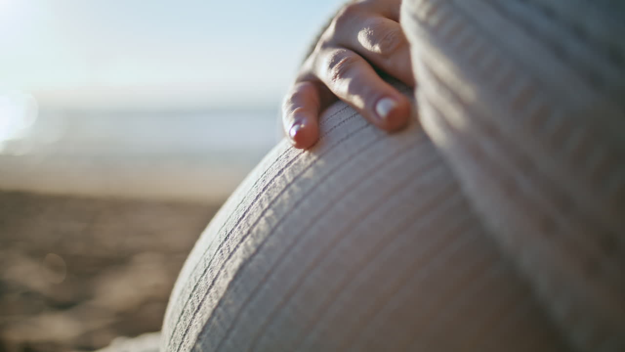 женщина ласкает живот, ожидая ребенка вблизи. беременный живот на закате