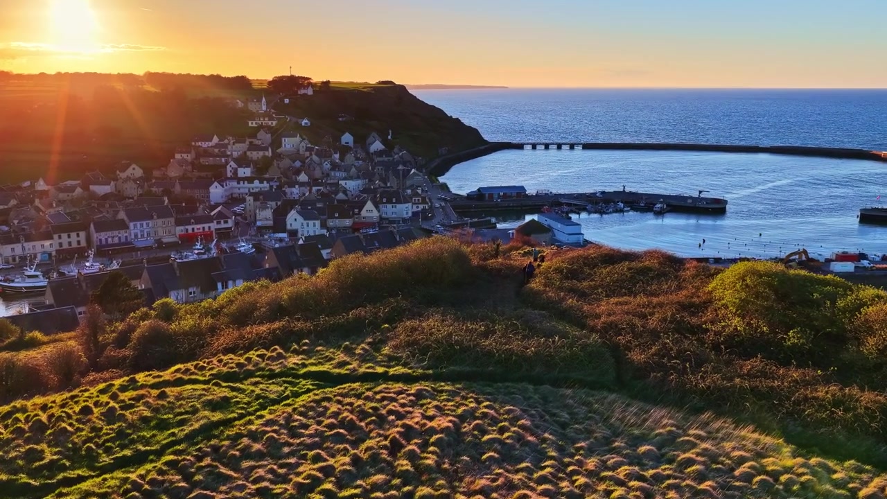 Betagende solnedgang over klippekyst med roligt hav og glødende himmel