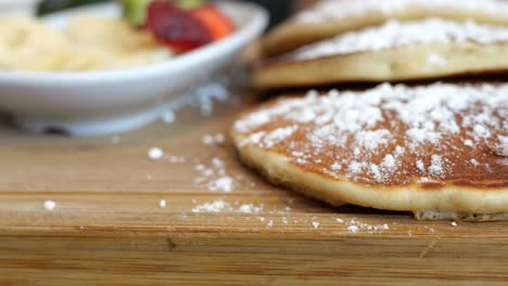 close-up of fluffy pancakes with powdered sugar and fresh fruit