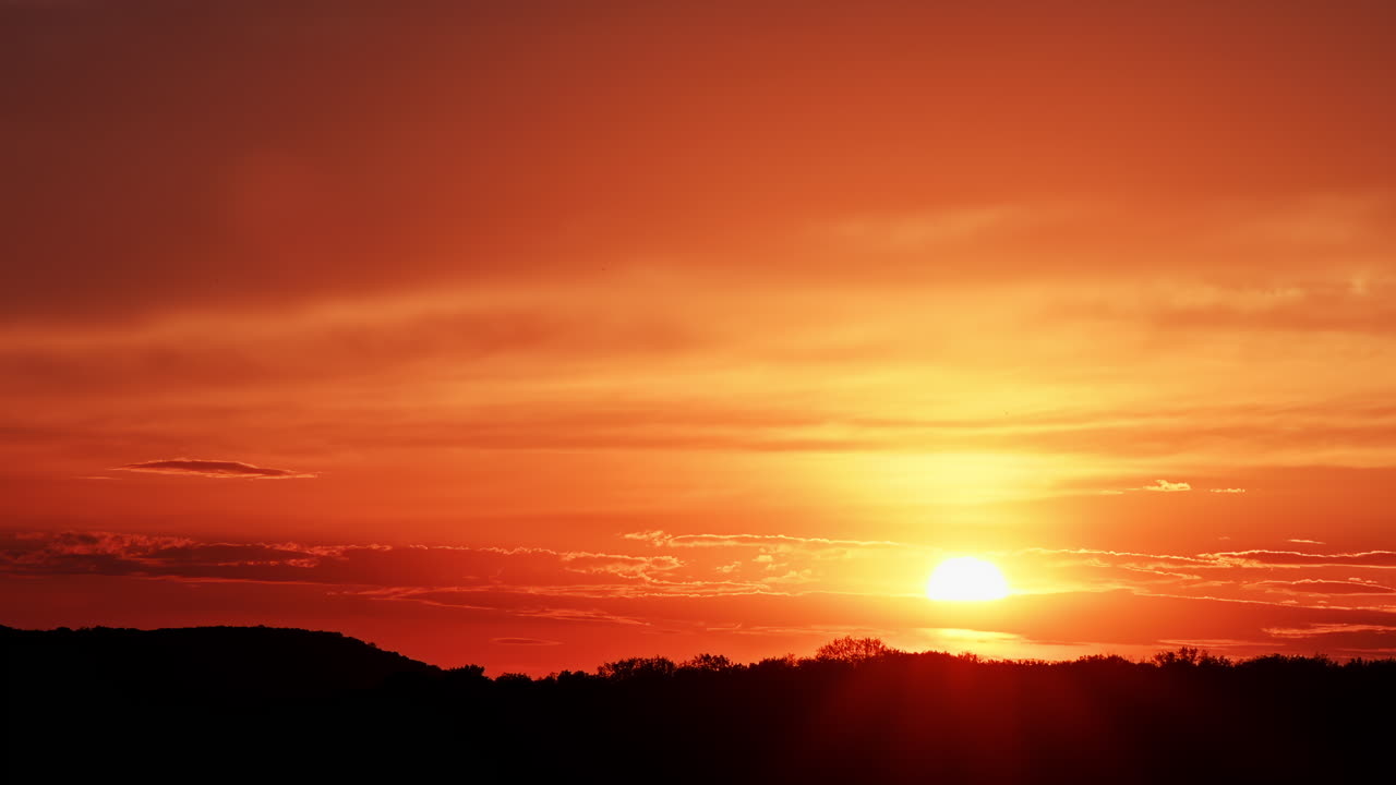 Scenic view of a dramatic red and orange sunset over hills and clouds