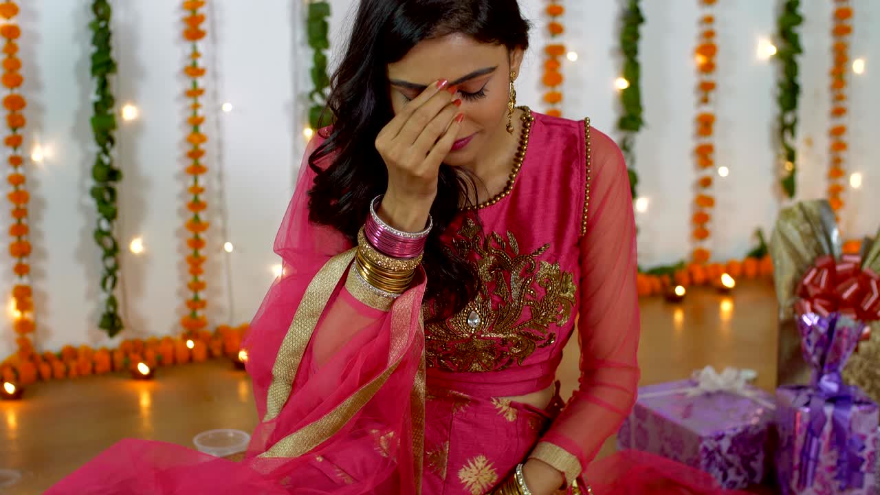 Beautiful young female smiling and putting on red bindi on her forehead on Diwali festival