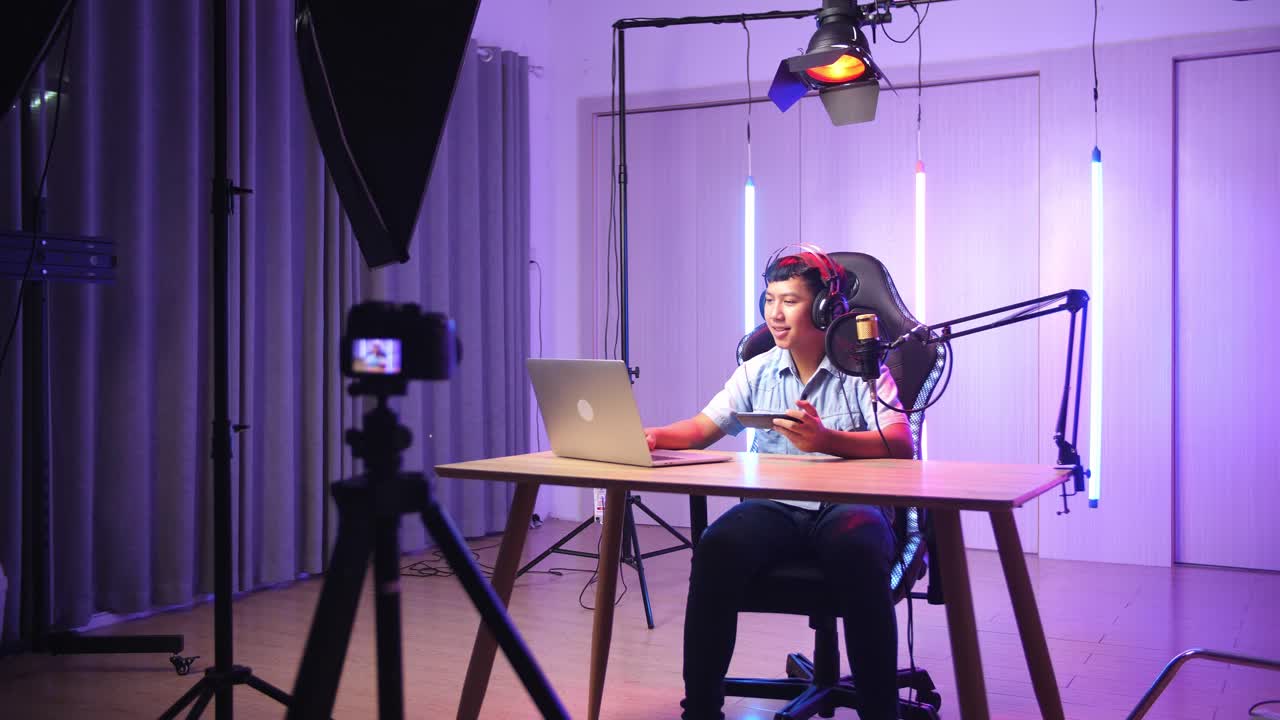 Asian Kid Boy Holding Mobile Phone And Read Comment In Laptop Computer Then Talking To Camera While Live Stream, Professional Light Equipment