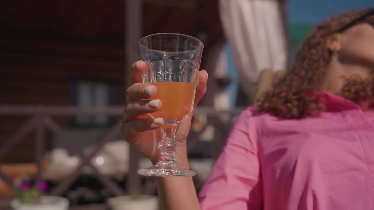 Bright Scene Captures Woman Celebrating Outdoors, Sunlit Image Features Cheerful Woman Raising Glass High, Vivid Photograph Depicts Happy Woman In Sunlight With Celebratory Attitude