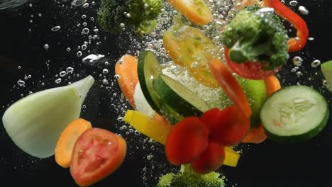 colorful vegetables falling into water on the black background