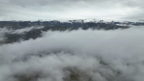 aerial view of snow-capped mountains emerging from a sea of clouds in iceland