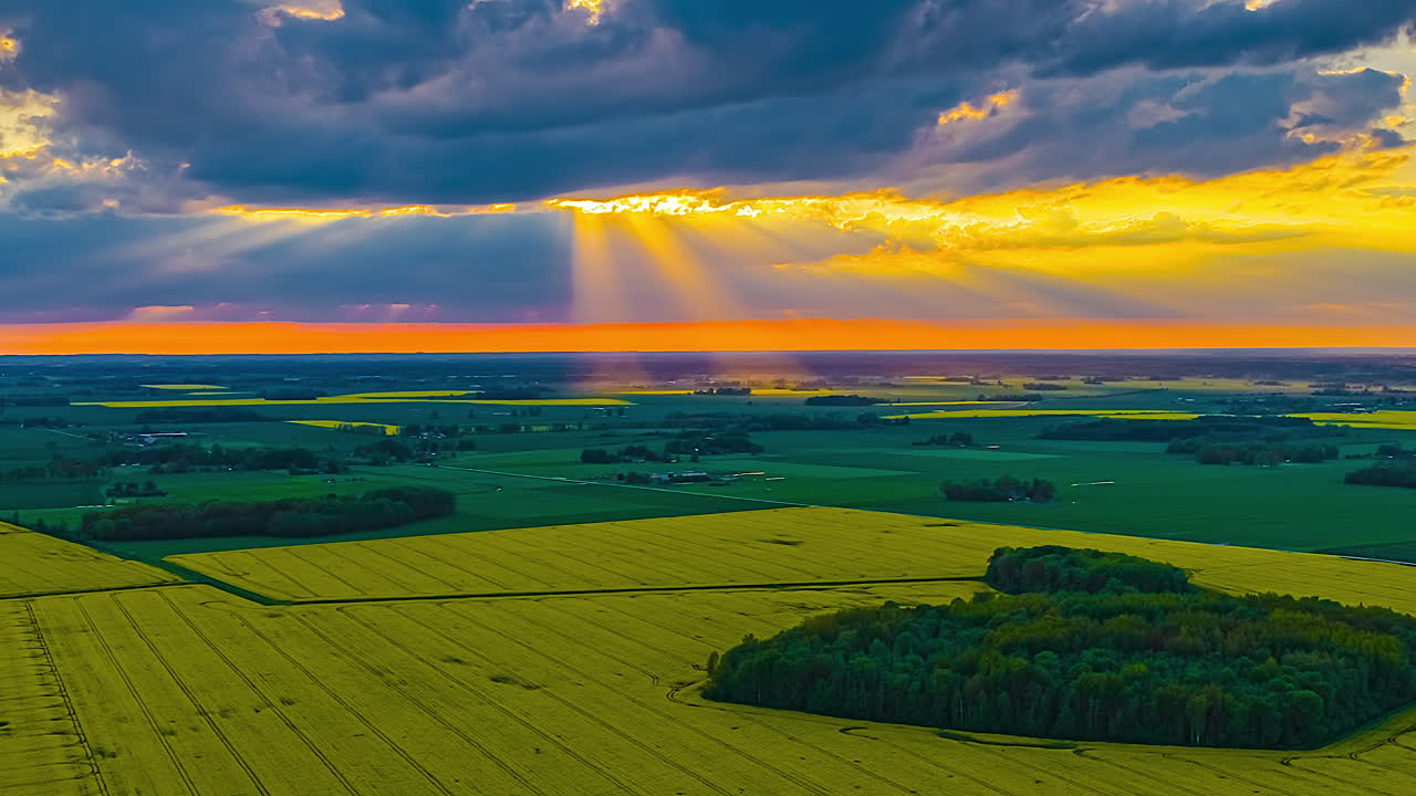 Glowing rays of sunshine at sunset shinning on the rural European countryside - high altitude aerial time lapse