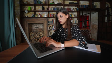mujer joven trabajando en una computadora portátil en una oficina en casa