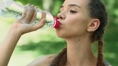 fitness woman drinking water from bottle after running exercise in city park