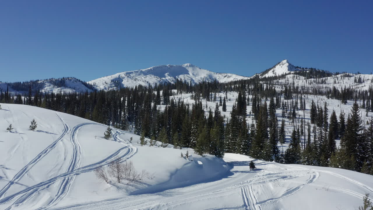 paisaje aéreo pasando motos de nieve conduciendo en una pintoresca carretera de montaña en el bosque