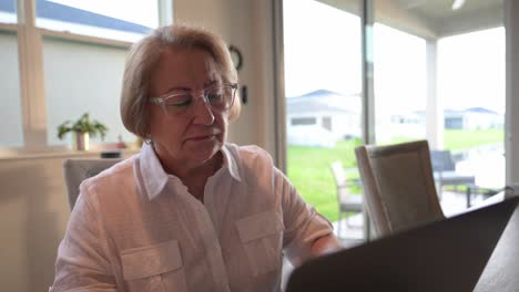 older woman receive unsettling disappointing news in an email on her laptop