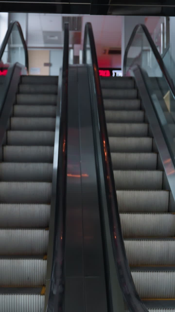 두 개의 에스컬레이터, 하나는 올라가고 다른 하나는 내려오고, 현대적인 실내 환경에서, 카메라는 에스클레이터의 대칭성과 기능성에 초점을 맞추고, 우아한 디자인과 사용을 강조합니다.