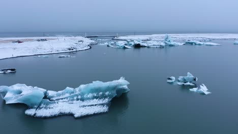 aerial drone shot of icelandic glacier lake with snowy icebergs during grey cloud at sky - jo kulsa rlo n in iceland - global warming concept