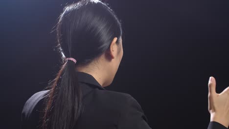 side view of asian speaker woman in business suit speaking in the black screen studio
