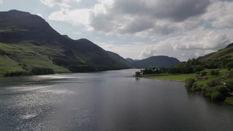 disparo de drones volando hacia adelante sobre el agua de crummock en un día soleado, lake district, cumbria, reino unido