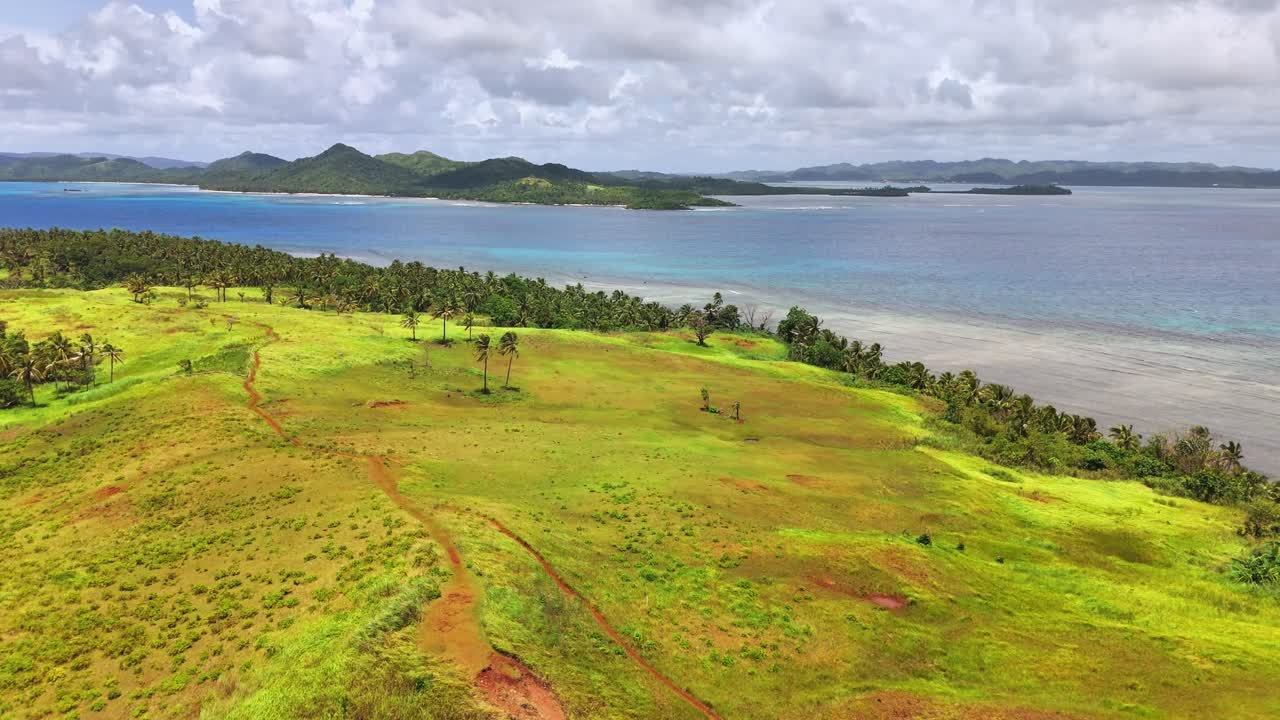 Aerial shot of Corregidor Island, Siargao, Philippines with cogon grass hills, coconut palms, and views of the Pacific Ocean and surrounding bays in a lush tropical coastal landscape