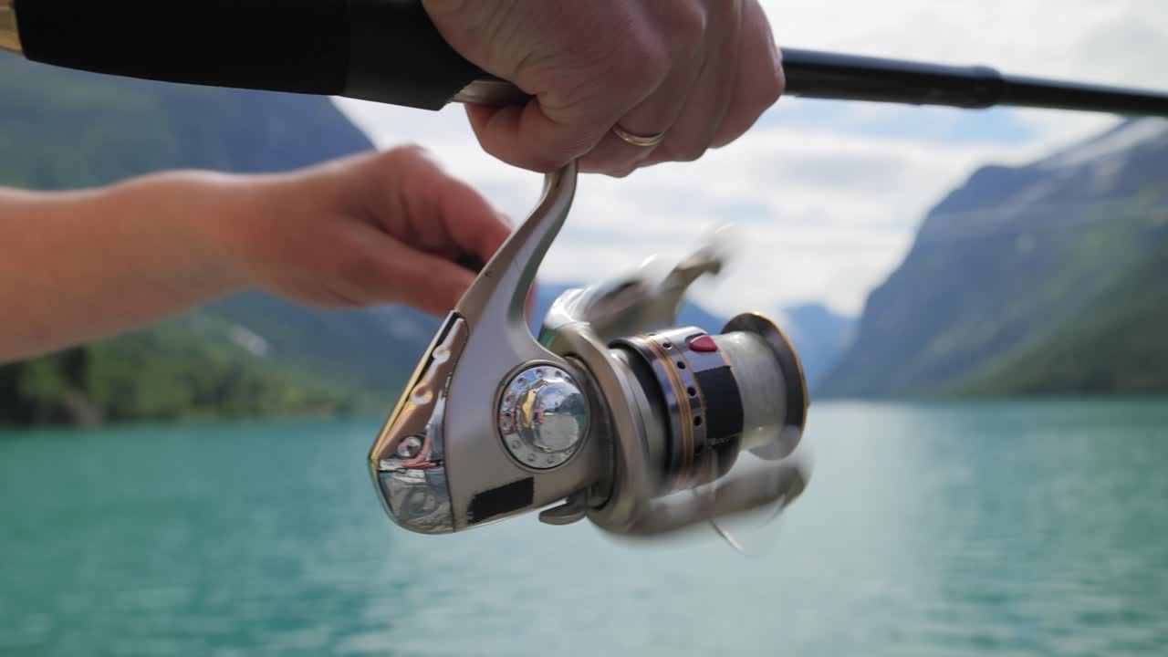 Pesca della donna sulla filatura della canna da pesca in Norvegia.