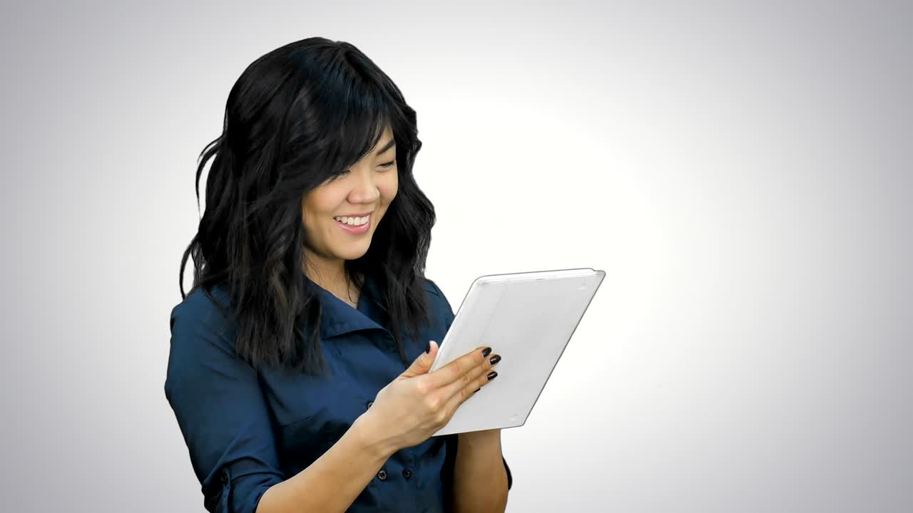 Smiling young woman working on tablet computer on white background