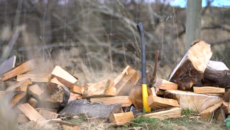 yellow axe leans against fence between piles of wood, static shot