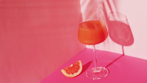 close up of drink with grapefruit on pink background