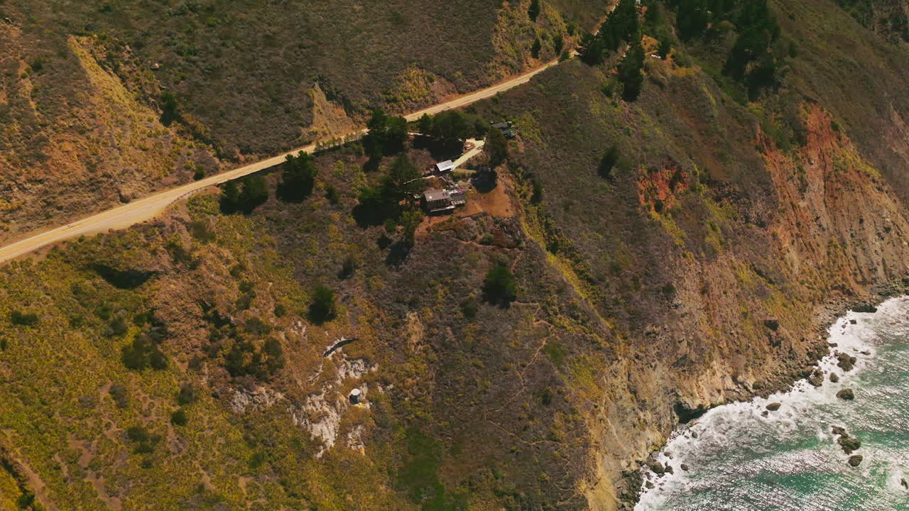 View of the houses build on the sloping mountains of the pacific coastline in California, USA. Motorway built in the mountains along the shore.