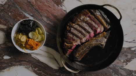 top-down shot of a ribeye steak being plated into a cast iron pan