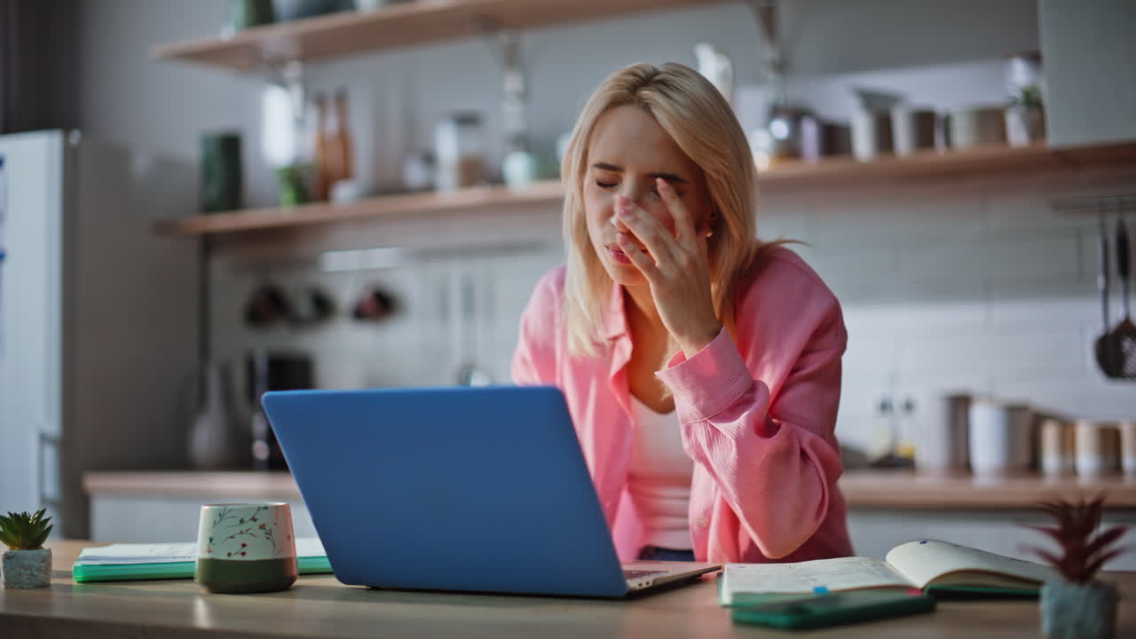 Shocked blonde staring laptop at kitchen closeup. Stressed woman finding mistake