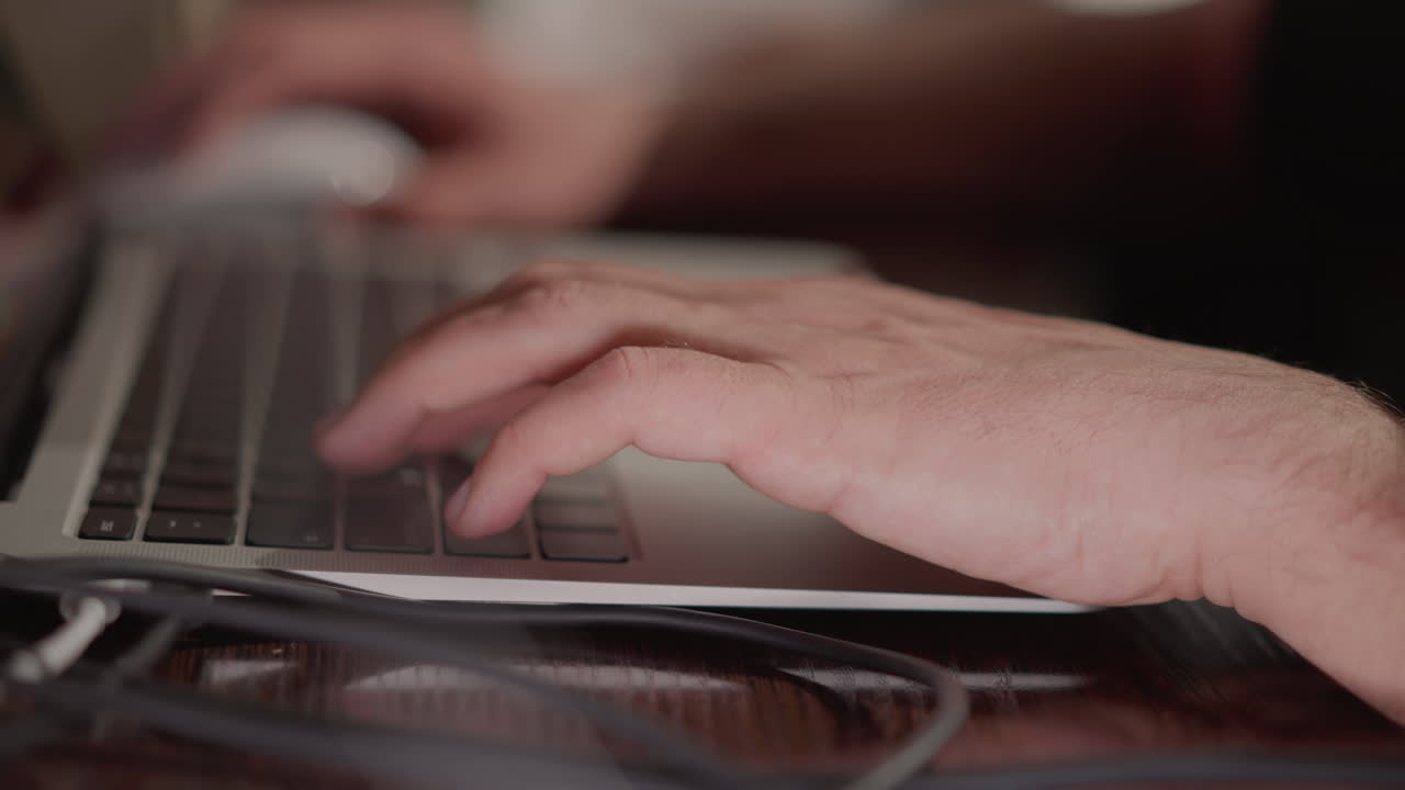 Close-up of a hand typing on a laptop keyboard, with the background blurred to emphasize the action. hand's movement and the focus on the task