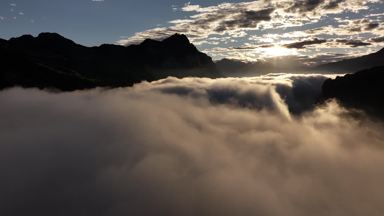 A serene aerial view over Walensee Lake in Switzerland, where mist and clouds gently envelop the surrounding mountains, creating a tranquil and picturesque landscape.