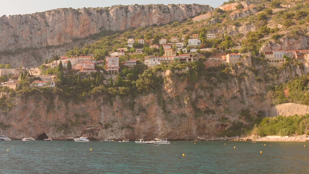 Lenta panoramica sul mare Mediterraneo turchese verso spettacolari scogliere calcaree con ville arroccate e barche ormeggiate