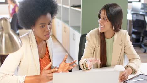 happy diverse female creative colleagues in discussion using laptop in office, slow motion