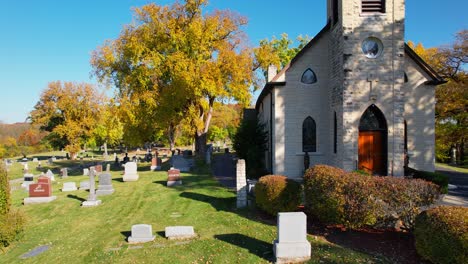 old small catholic church with cemetry headstones and bright autumn trees