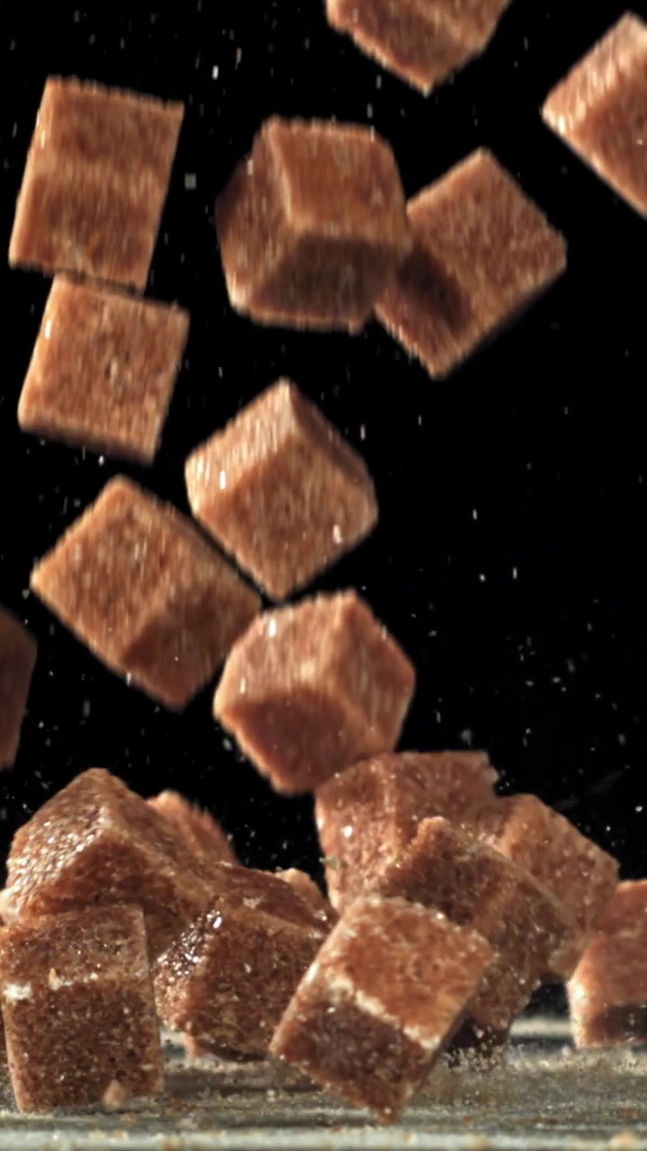 Brown Sugar Cubes Falling in Slow Motion on Black Background