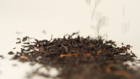 Macro-shot-of-Black-tea-falling-on-white-ground-in-100-FPS